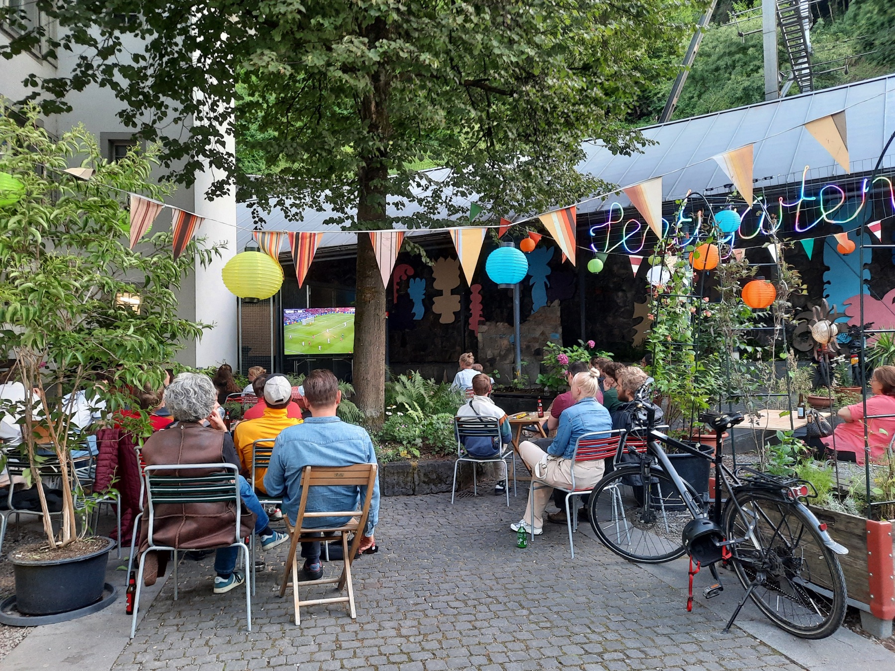 Menschen bei einer Veranstaltung im sommerlich dekorierten Sentigarten
